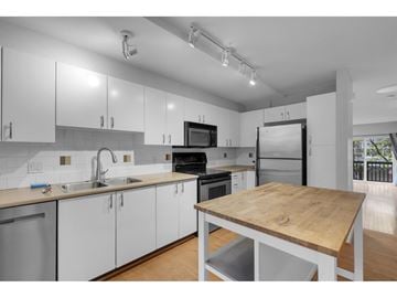 Surrey townhouse for rent - A kitchen with white cabinets and a wooden island.