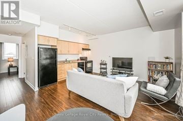 Guelph (Downtown) condo for rent - A living room with a white couch and a black refrigerator.