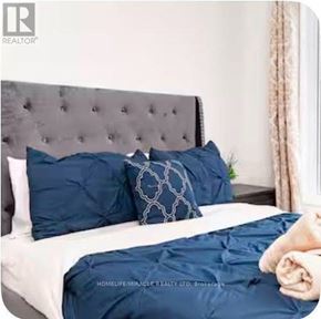 Brampton (Credit Valley) townhouse for rent - A bed with a grey headboard and blue pillows.