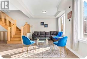 Brampton (Credit Valley) townhouse for rent - A living room with a grey couch, blue chairs, and a wooden staircase.