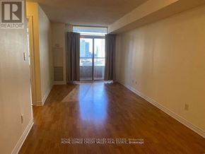 Mississauga (City Centre) condo for rent - A room with wooden floors and white walls, with a door on the left and a window with curtains on the right.