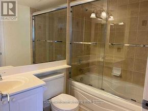 Mississauga (City Centre) condo for rent - A bathroom with a glass shower door and a white toilet.