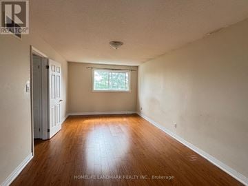 Barrie (Letitia Heights) apartment for rent - A room with wooden floors and a window with a view of trees.