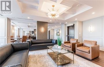 Hamilton (Waterdown) condo for rent - A living room with a black couch and a glass coffee table.