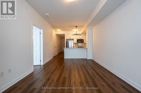 Hamilton (Waterdown) condo for rent - A long, empty room with wood floors and white walls.