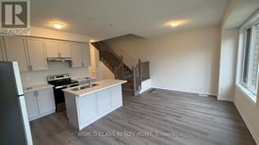 Kawartha Lakes (Lindsay) townhouse for rent - A spacious kitchen with a stove top oven and a staircase in the background.