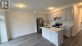 Kawartha Lakes (Lindsay) townhouse for rent - A realtor brokerage image of a kitchen with white cabinets and a stainless steel refrigerator.