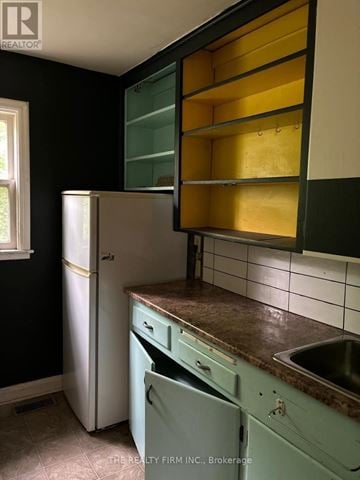 London East (East F) fourplex for rent - A kitchen with a white fridge and green cabinets.