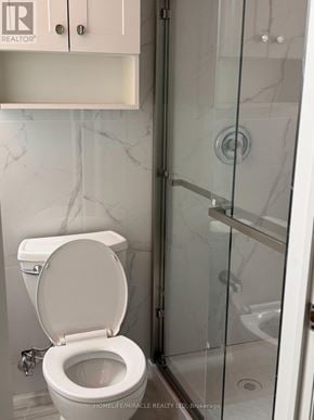 Toronto (Eglinton East) apartment for rent - A white toilet in a bathroom with a glass shower door.