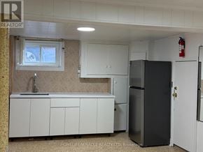 Toronto (Eglinton East) apartment for rent - A kitchen with white cabinets and a black fridge.
