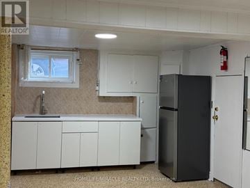 Toronto (Eglinton East) apartment for rent - A kitchen with white cabinets and a black fridge.