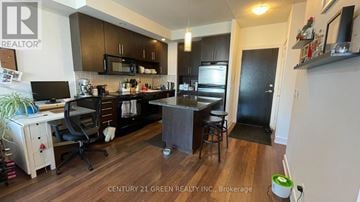 Toronto (North St. James Town) condo for rent - A kitchen with a black refrigerator and wooden floors.