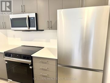 Guelph (Clairfields/Hanlon Business Park) townhouse for rent - A stainless steel refrigerator stands next to a microwave and oven in a kitchen.