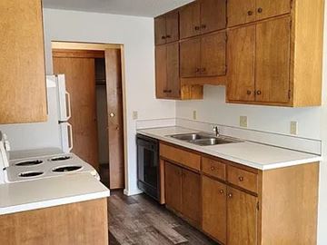 Fargo apartment for rent - A kitchen with wooden cabinets and a white stove top oven.