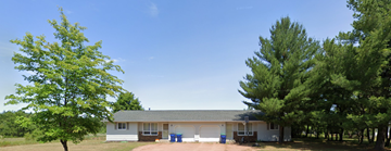 Kronenwetter apartment for rent - A house with a grey roof and white walls is surrounded by trees.