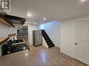 Niagara Falls (Forestview) apartment for rent - A kitchen with a stove top oven and a refrigerator in a white room.