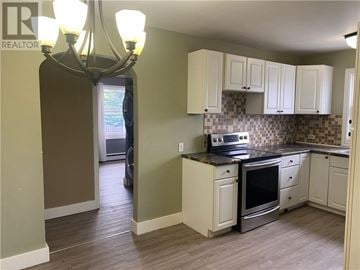 Garson apartment for rent - A kitchen with a stove top oven and a chandelier.