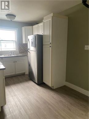 Garson apartment for rent - A kitchen with a refrigerator and a sink.