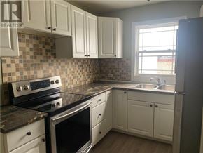Garson apartment for rent - A kitchen with white cabinets and a black stove top oven.