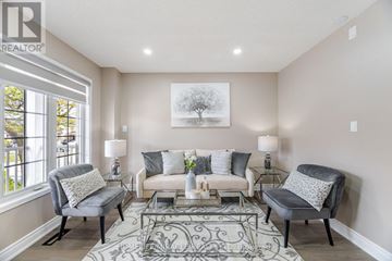 Brampton (Fletcher's Meadow) apartment for rent - A living room with a grey sofa, two grey armchairs, and a glass coffee table with a white vase on it.