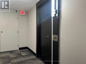 Mississauga (City Centre) condo for rent - A black door with the number 304 on it is in a room with a white wall and a brokerage logo.