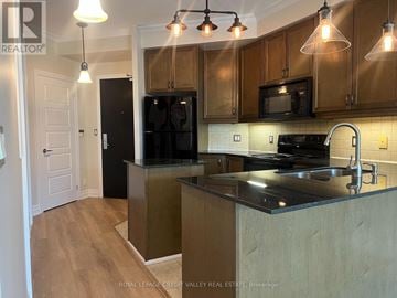 Mississauga (City Centre) condo for rent - A kitchen with wooden cabinets and black appliances.