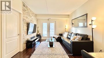 Burlington (Tansley) condo for rent - A living room with a black couch and a stone wall.