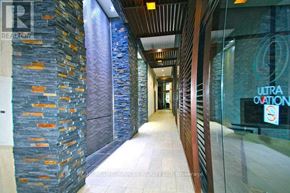 Mississauga (City Centre) condo for rent - A hallway with a stone wall on the left and a glass wall on the right with a sign that says "ULTRA OVATION".