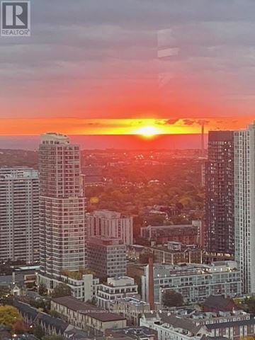 Toronto (Church-Yonge Corridor) condo for rent - A cityscape with buildings of various heights and a sunset in the background.