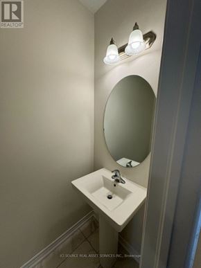 Kitchener apartment for rent - A white sink in a bathroom with a round mirror above it.