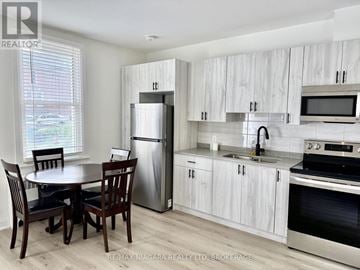 Niagara Falls (Downtown) multi-family for rent - A kitchen with a table and chairs in front of a window.