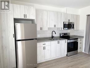 Niagara Falls (Downtown) multi-family for rent - A modern kitchen with white cabinets and stainless steel appliances.