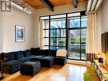 Toronto (Niagara) condo for rent - A living room with a large black couch and a wooden floor.