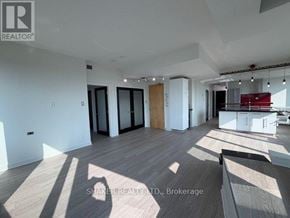 Ottawa condo for rent - A spacious room with wooden flooring and white walls, currently empty and ready for furnishing.