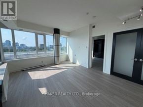 Ottawa condo for rent - A spacious room with wooden flooring and large windows overlooking a cityscape.