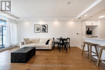 Toronto (Willowdale West) condo for rent - A living room with a white couch, a black coffee table, and a dining table with chairs.