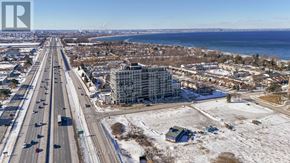 Hamilton (Lakeshore) condo for rent - A highway with multiple lanes in each direction, surrounded by buildings and a body of water in the distance.