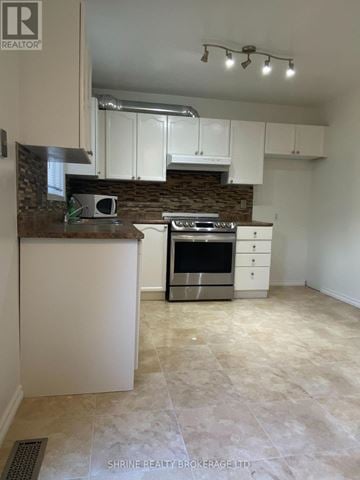 London North (North I) townhouse for rent - A kitchen with white cabinets and a stone backsplash.
