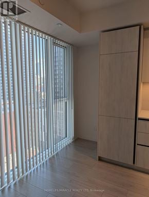 Toronto (Waterfront Communities) condo for rent - A room with a wooden floor and a large window with blinds.