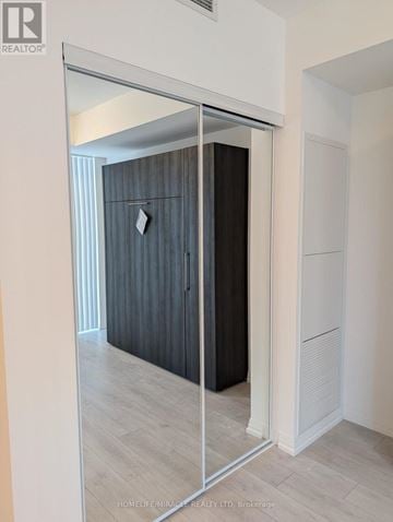 Toronto (Waterfront Communities) condo for rent - A modern bedroom with a large wardrobe and a mirrored door.