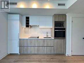 Toronto (Moss Park) condo for rent - A kitchen with white cabinets and a wooden countertop.
