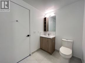 Toronto (Moss Park) condo for rent - A white toilet sits next to a sink in a small bathroom.