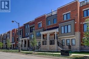 Oakville (Jm Joshua Meadows) townhouse for rent - A row of modern townhouses with a clear blue sky above.