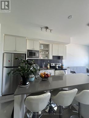 Toronto (Downsview-Roding-Cfb) condo for rent - A modern kitchen with white cabinets and a stainless steel refrigerator.