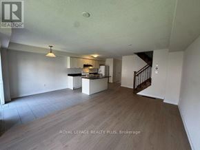 Hamilton (Stoney Creek Mountain) townhouse for rent - A spacious room with a kitchen area and a staircase.