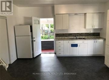St. Catharines (Downtown) duplex for rent - A kitchen with white cabinets and a refrigerator.