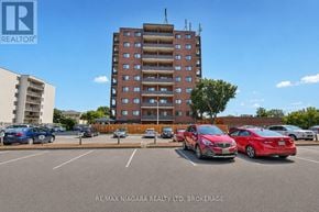 Niagara Falls (Stamford) condo for rent - A parking lot with cars and a tall building in the background.