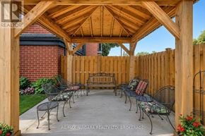 Niagara Falls (Stamford) condo for rent - A wooden pergola with metal chairs and a table is set up in a backyard.
