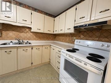 Niagara Falls (Stamford) condo for rent - A kitchen with white cabinets and a white stove top oven.