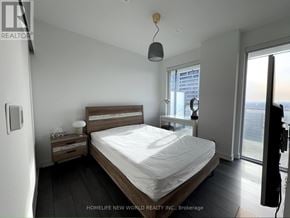 Toronto (Church-Yonge Corridor) condo for rent - A bedroom with a large bed, nightstand, and a window overlooking the city.